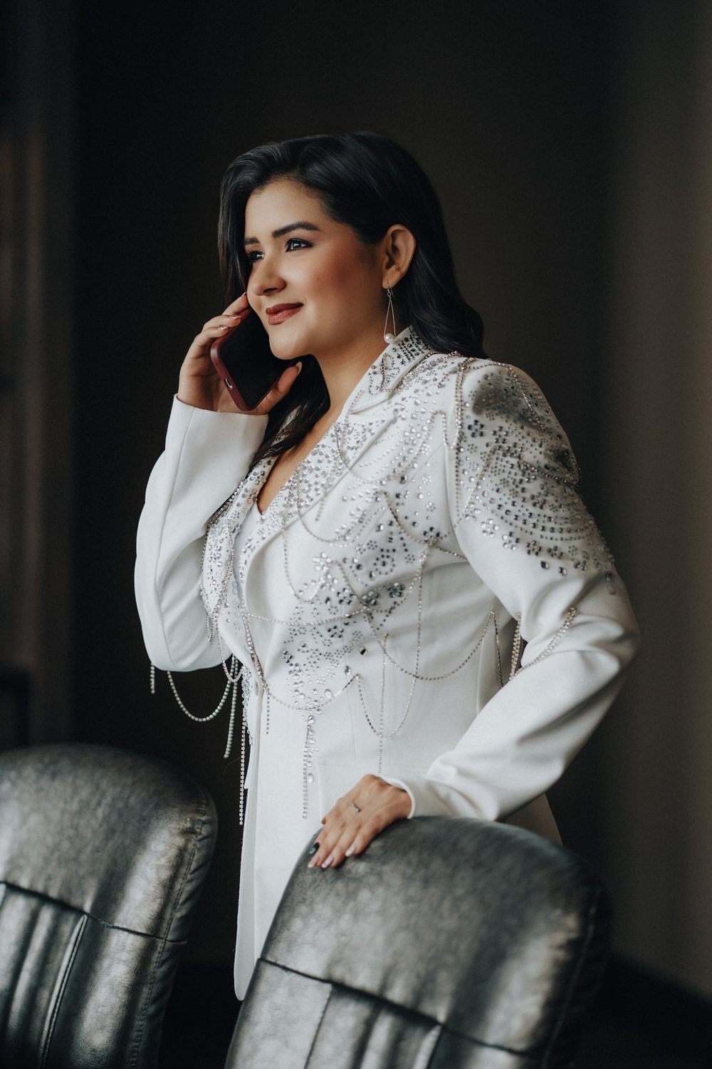 Mary Claudia Andrade atendiendo una llamada, con traje blanco